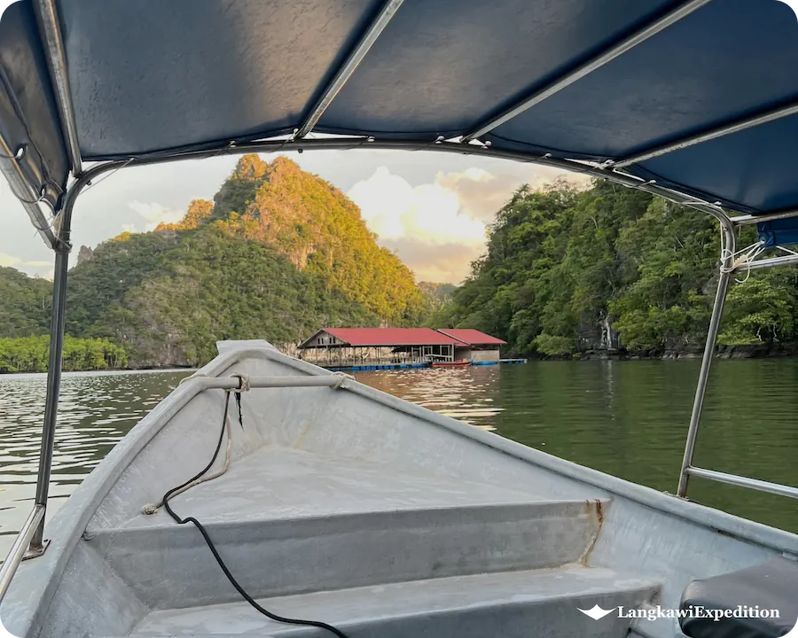 Front boat view approaching the floating fish farm restaurant surrounded by limestone karst