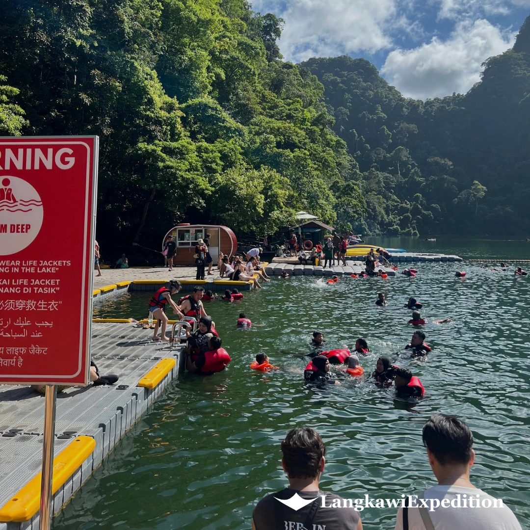 Tourists in red life jackets swimming from floating pontoon docks at Lake of the Pregnant Maiden in Langkawi