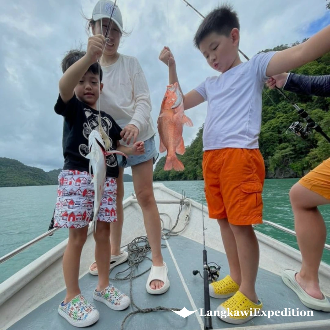 Happy family displaying fresh fish catches on a Kilim mangrove fun fishing boat tour in Langkawi
