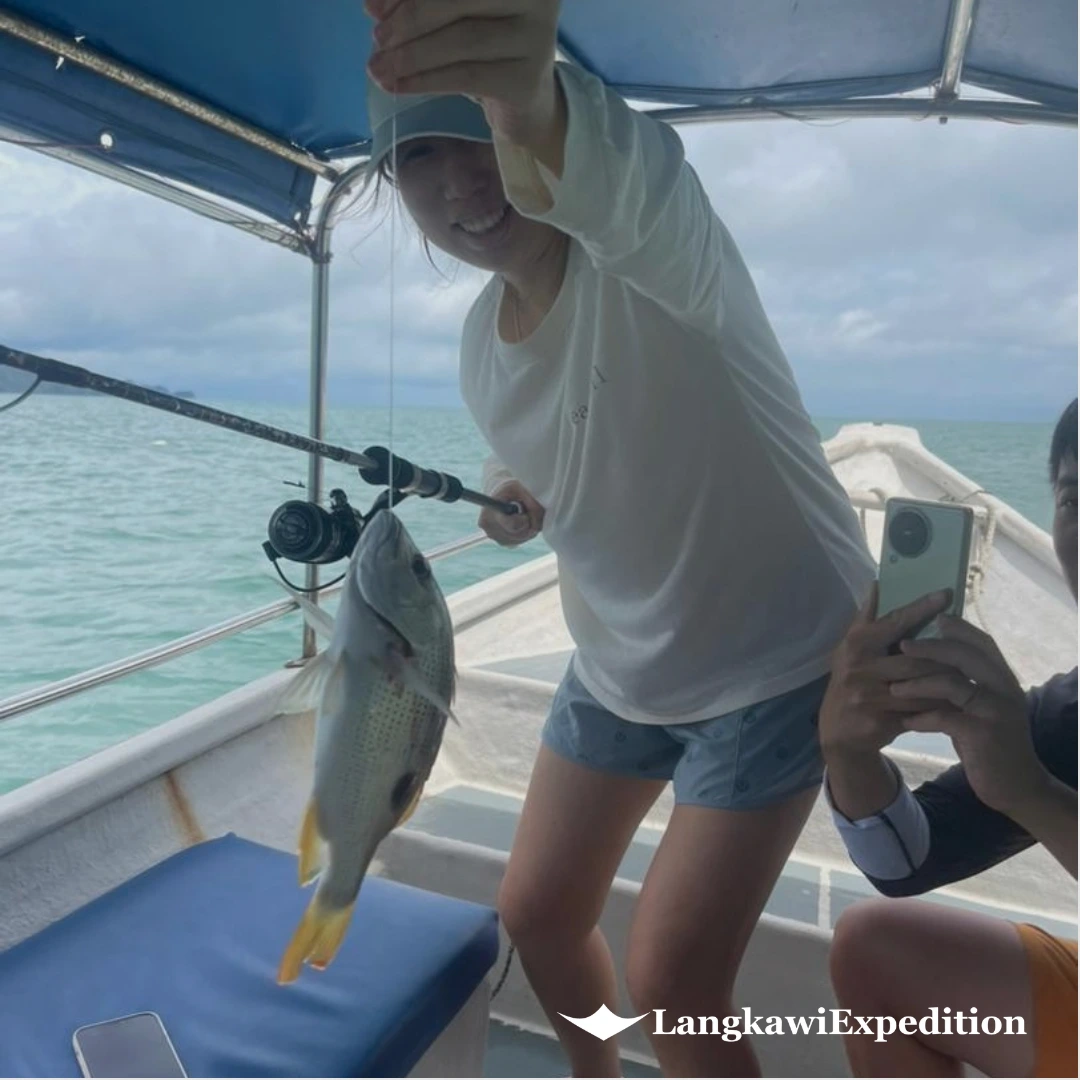 Guest holding a fish caught using traditional bottom handline fishing in Kilim Geoforest Langkawi